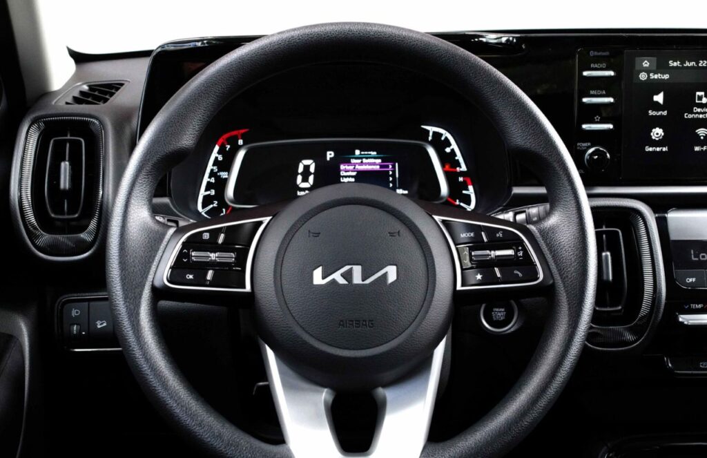 The interior of a Kia car, showing the steering wheel and the main control panel.