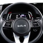 The interior of a Kia car, showing the steering wheel and the main control panel.