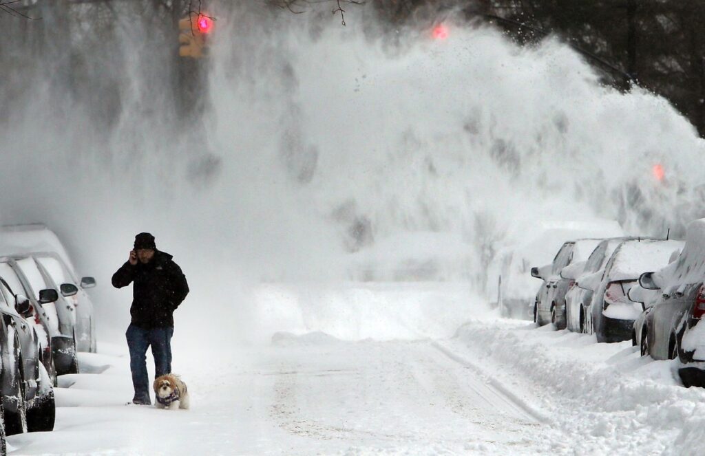 Maximum alert in New York due to powerful snowstorm after Christmas A person walking down a snow-covered street with many parked cars