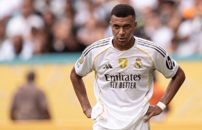 Mbappé standing on the pitch with a worried expression