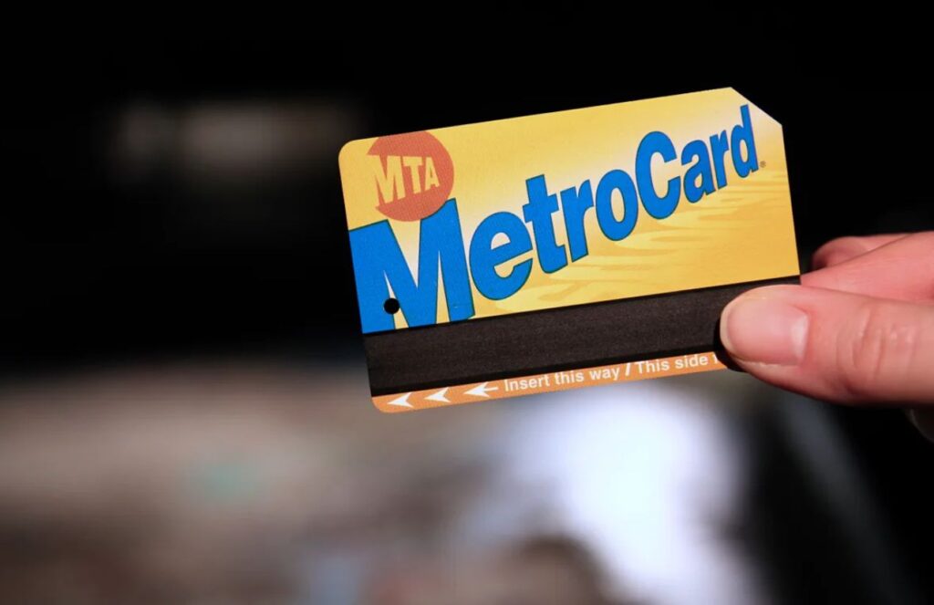 A person holding a yellow and blue MetroCard