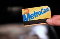 A person holding a yellow and blue MetroCard