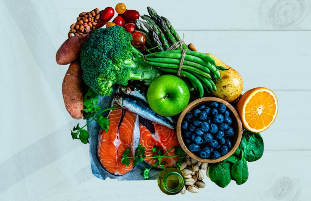 Various vegetables, fruits, and fish in a bowl on top of a table