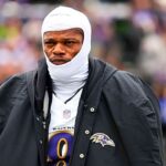 The leader of the Ravens’ offense wearing his white uniform with a large coat over it as he walks toward the locker room