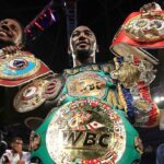 The iconic American boxer raising several of his championship belts in the middle of a boxing ring