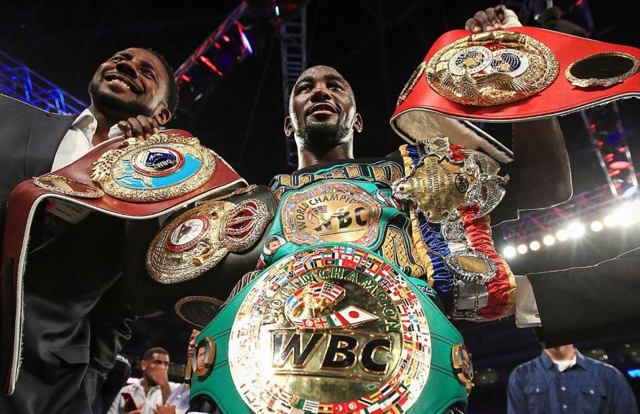 The iconic American boxer raising several of his championship belts in the middle of a boxing ring
