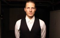 The renowned actor posing for the camera in an elegant suit against a completely black background