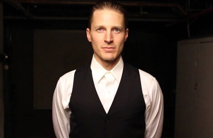 The renowned actor posing for the camera in an elegant suit against a completely black background