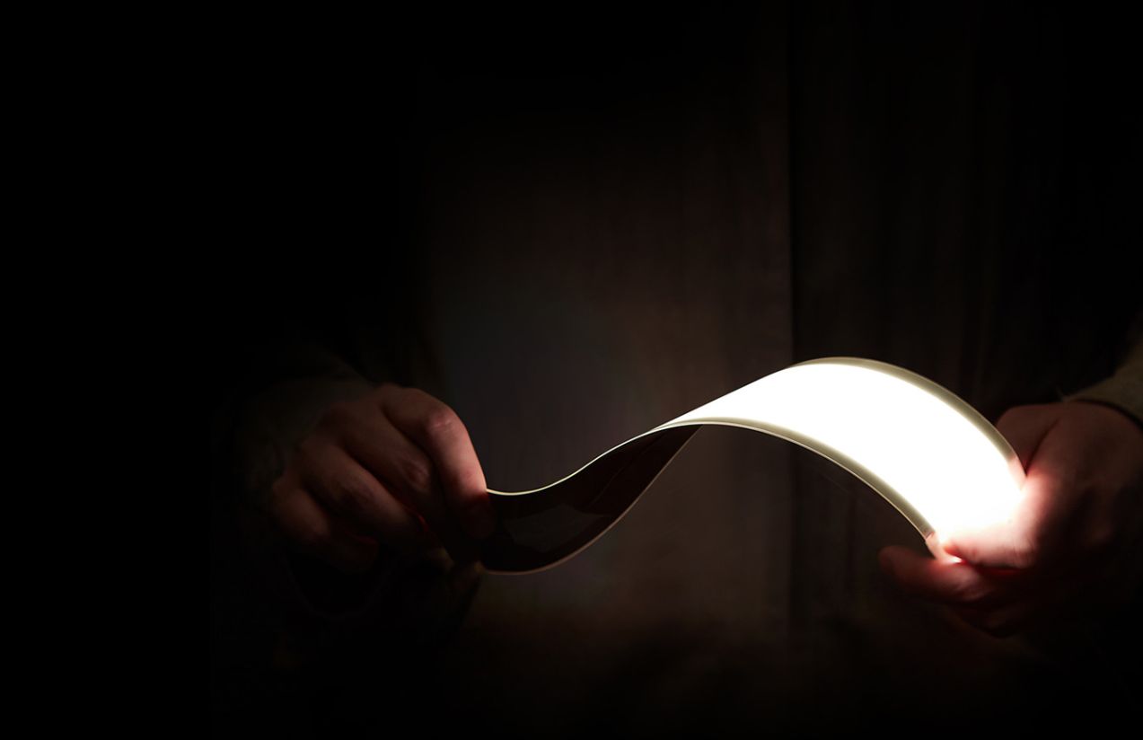 A person holding an OLED light panel with their hands