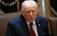 Donald Trump with an angry expression, sitting in an office, wearing an elegant suit