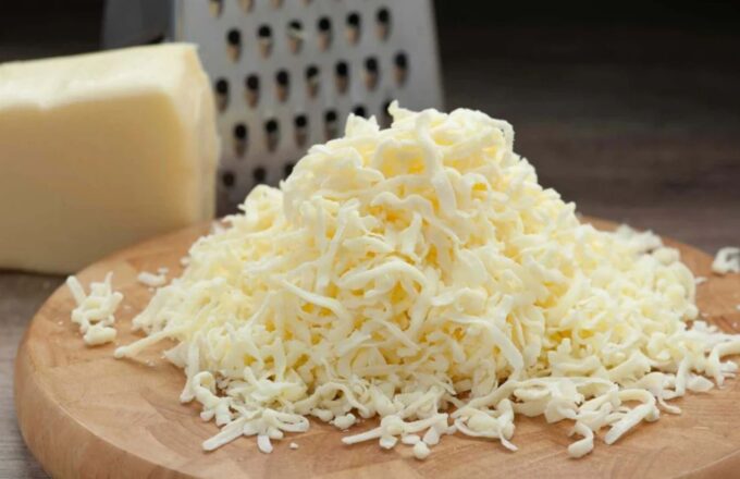 A bit of freshly shredded mozzarella cheese on a wooden board