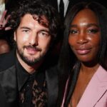 The legendary tennis player posing with her partner for a photo, wearing a beautiful purple dress