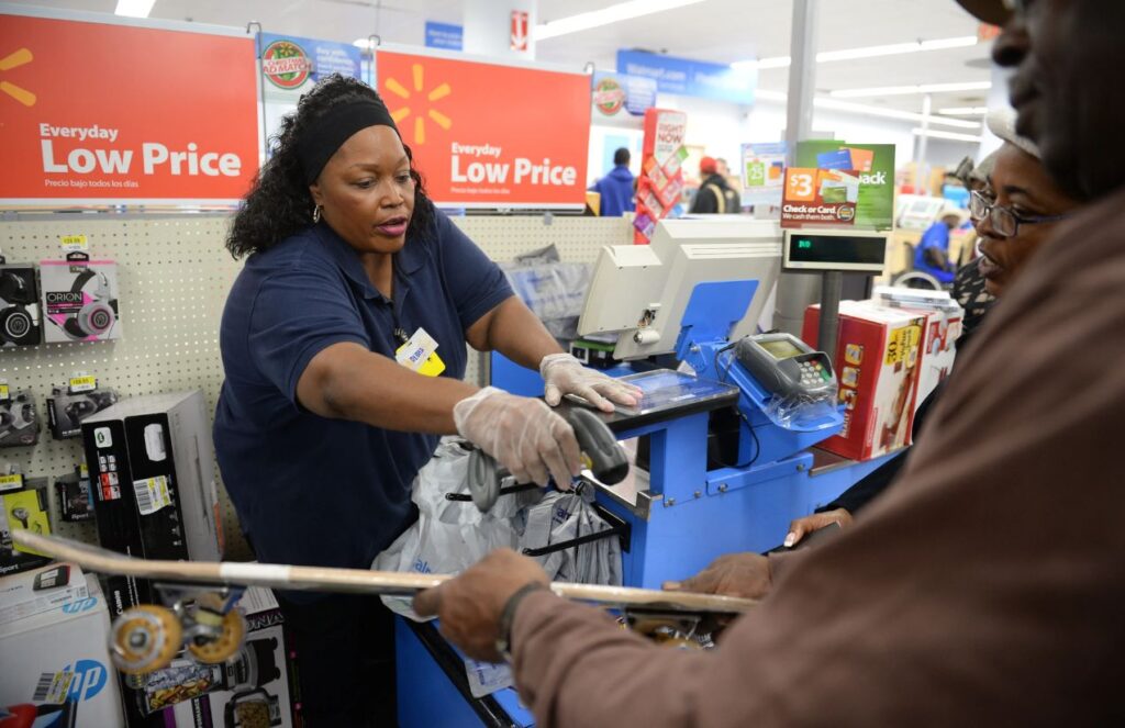 A Walmart employee assisting different customers inside the store