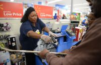 A Walmart employee assisting different customers inside the store