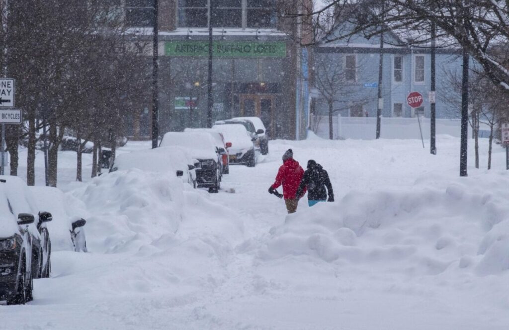 Two people walking through the snowstorm that hit New York