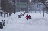 Two people walking through the snowstorm that hit New York