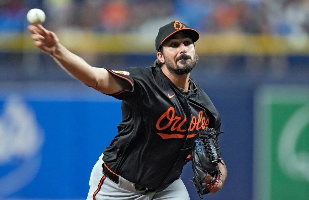 The right-handed pitcher on the mound, stretching his arm to deliver a pitch