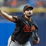 The right-handed pitcher on the mound, stretching his arm to deliver a pitch