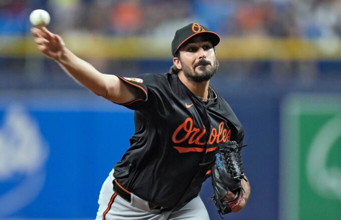 The right-handed pitcher on the mound, stretching his arm to deliver a pitch