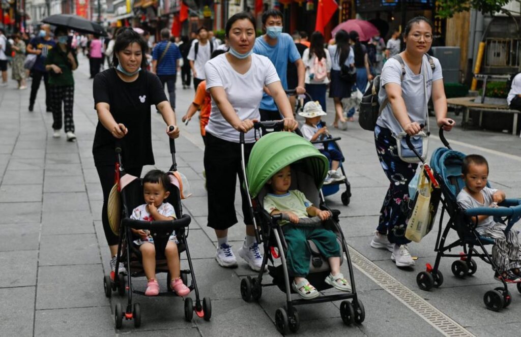 Three women pushing strollers with their babies while walking through the streets of China