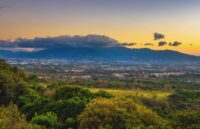 A city in Costa Rica seen from the mountains, showing a green and gray contrast between nature and the city