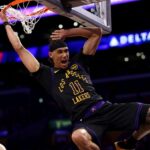 The young Lakers player hanging from the basketball rim in a flashy way