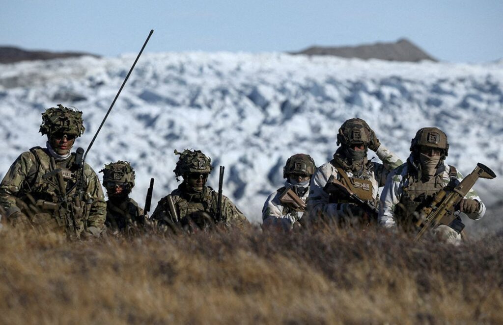 Several German military personnel walking through the cold mountains of Greenland during one of their patrols