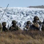 Several German military personnel walking through the cold mountains of Greenland during one of their patrols