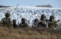 Several German military personnel walking through the cold mountains of Greenland during one of their patrols