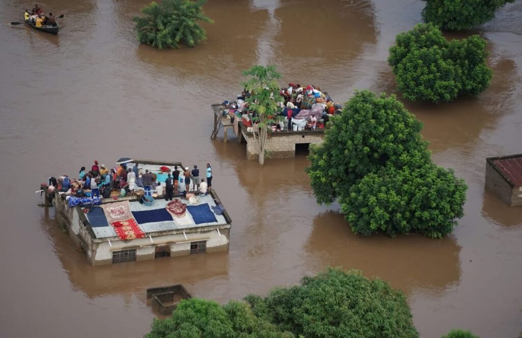 Historic floods in Mozambique displace nearly 400,000 people Houses submerged in floodwaters, with people standing on rooftops to avoid being swept away
