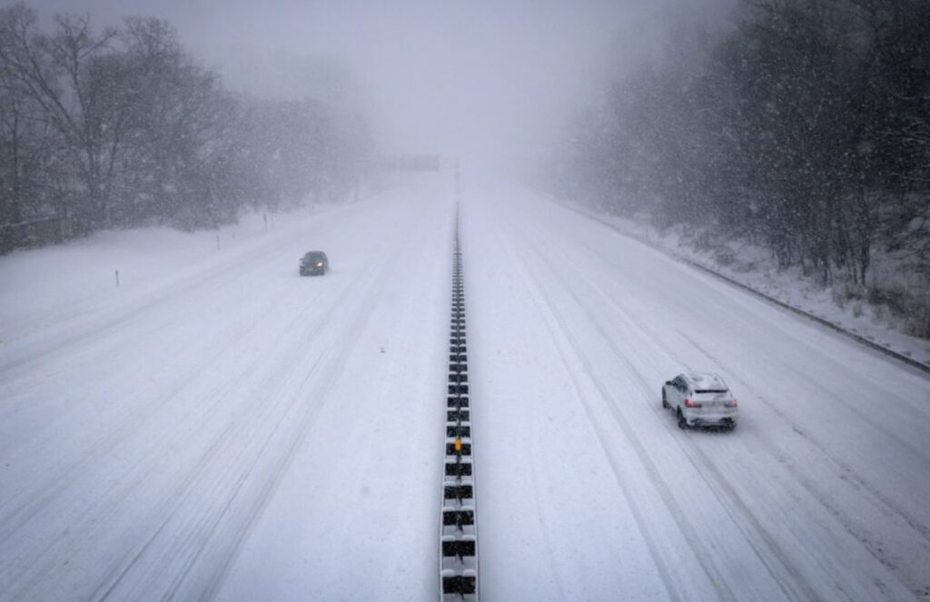 Two major highways in the United States covered in snow on all sides while two cars drive through