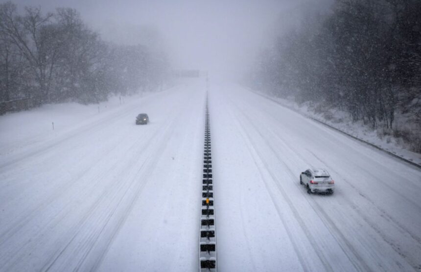 Two major highways in the United States covered in snow on all sides while two cars drive through