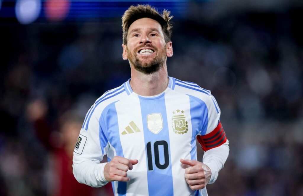 Messi wearing his national team jersey, smiling after scoring a goal and celebrating it with his fans