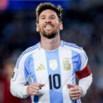 Messi wearing his national team jersey, smiling after scoring a goal and celebrating it with his fans