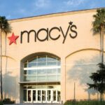 A panoramic view of a large Macy’s store with its red logo and a beige-colored building