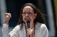 The Venezuelan opposition leader encouraging her supporters while speaking into a microphone with a firm and determined tone
