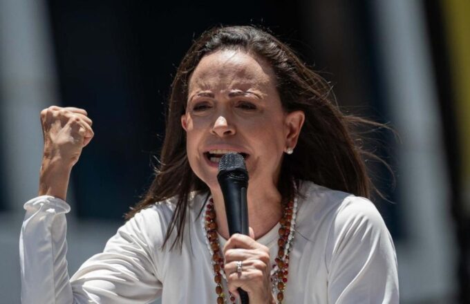 The Venezuelan opposition leader encouraging her supporters while speaking into a microphone with a firm and determined tone