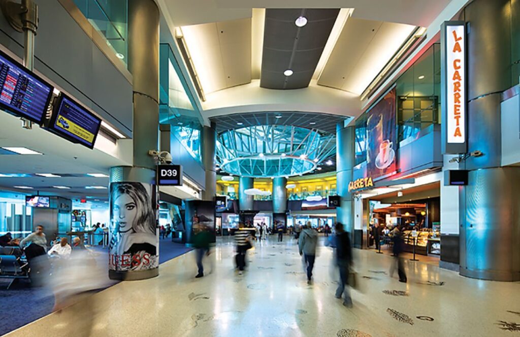Miami suspends flights to the Caribbean after the capture of Nicolás Maduro An interior view of Miami International Airport, with many lights and several people looking for their flights