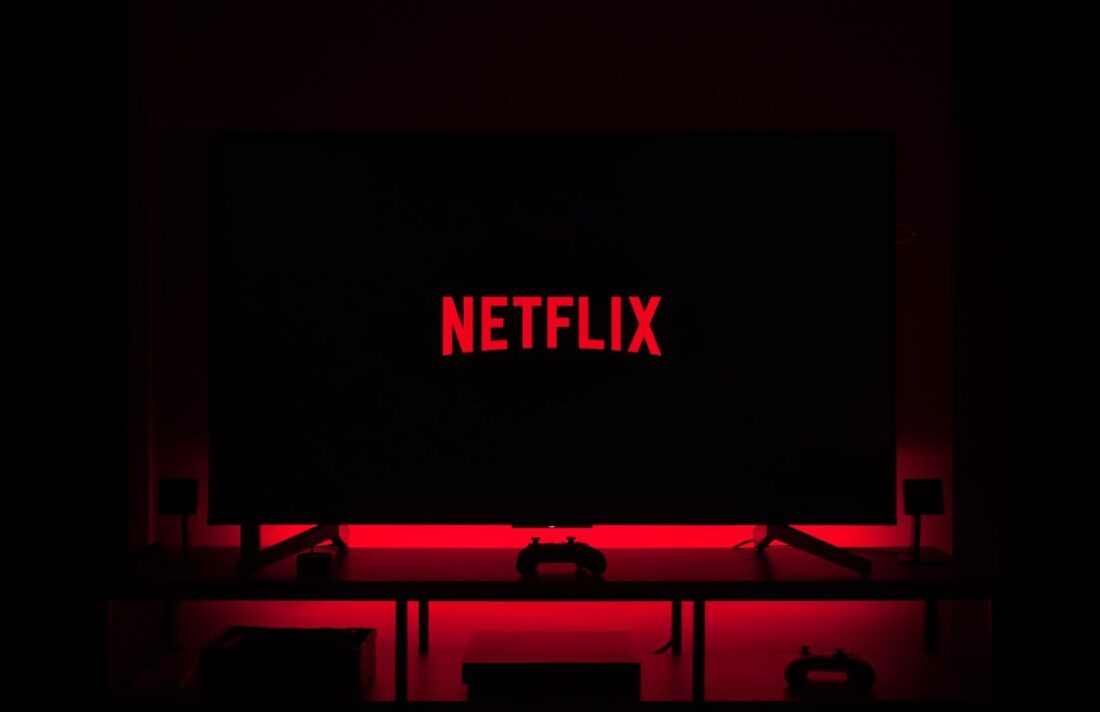 A room in complete darkness, with only a television surrounded by red lights and the word “Netflix” in the center