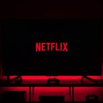 A room in complete darkness, with only a television surrounded by red lights and the word “Netflix” in the center