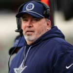 Mike wearing Cowboys coach attire, giving instructions through his headset