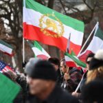 A crowd of people holding Iranian flags and some signs calling for freedom