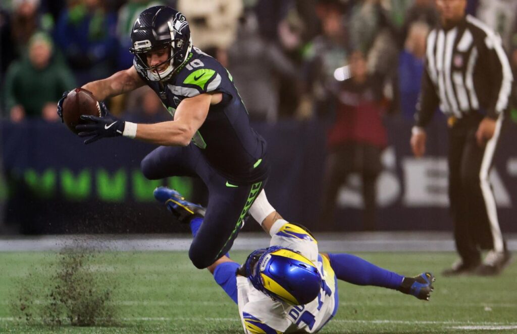 A Seattle player stretching out to score while a Rams player grabs him by the waist