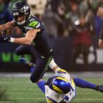 A Seattle player stretching out to score while a Rams player grabs him by the waist