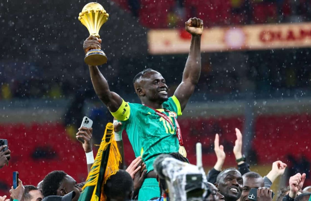 Sadio Mané lifting the championship trophy while his teammates carry him on their shoulders