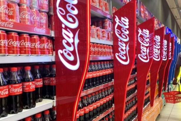 A supermarket shelf filled with many Coca-Cola products and other sugary beverages