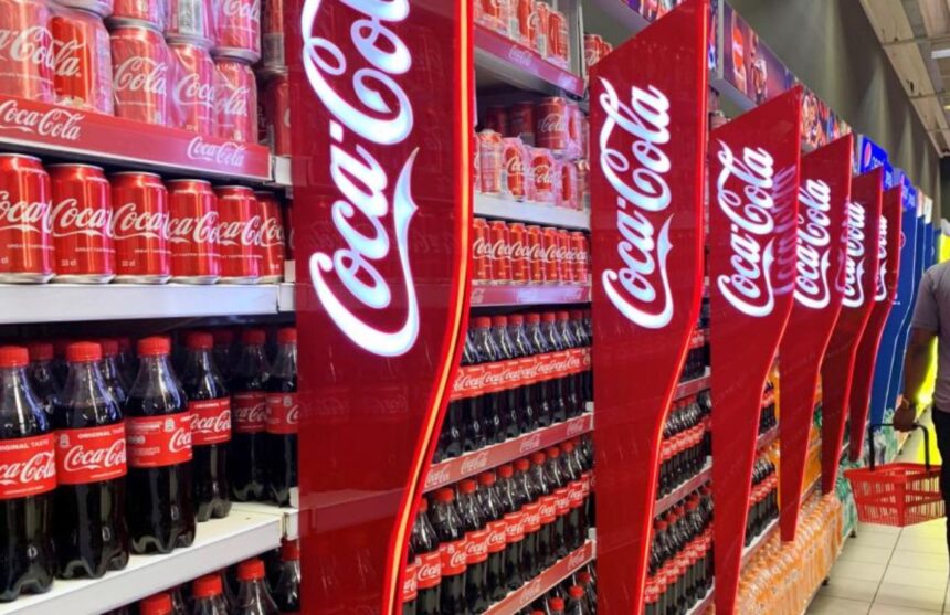 A supermarket shelf filled with many Coca-Cola products and other sugary beverages