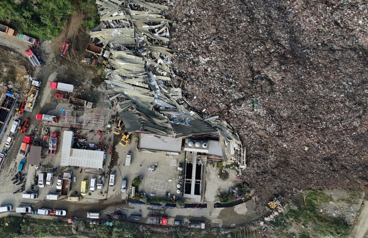 An aerial view of what happened in the Philippines, showing a massive garbage landslide and numerous emergency vehicles surrounding the area