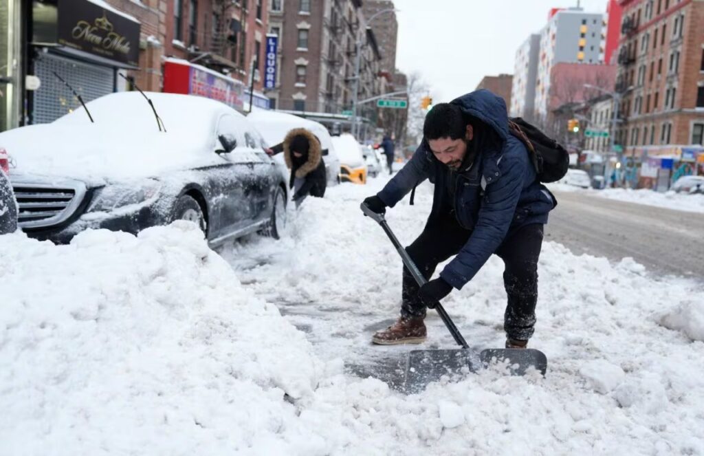 A person clearing snow from the streets as snowfall continues in the United States