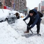 Travelers face a chaotic week after a winter storm hits the United States A person clearing snow from the streets as snowfall continues in the United States